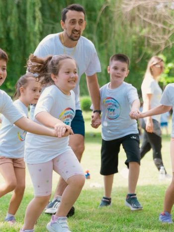 Children joyfully running and holding hands in a sunny park, enjoying outdoor recreation.